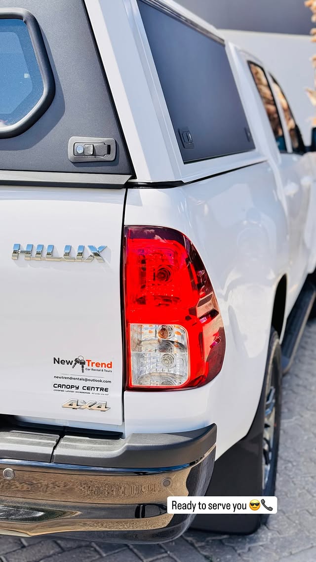 Rear of a New Trend Car Rental Toyota Hilux with the company branding